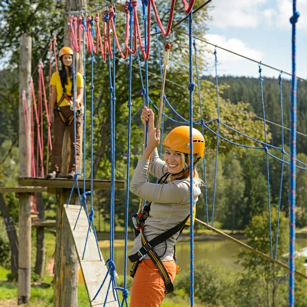 Woman climbing rope ladder in adventure park