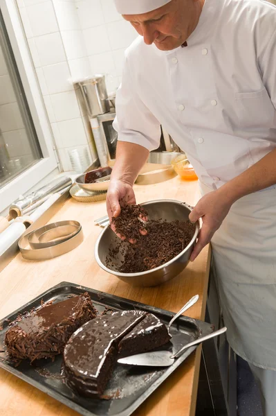 Cook adding chocolate sauce cake in kitchen