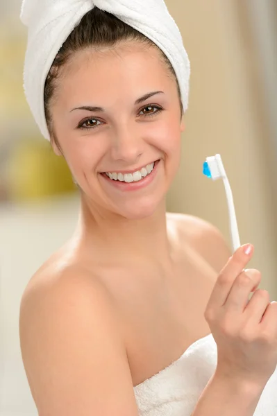 Fresh girl wrapped in towel brushing teeth