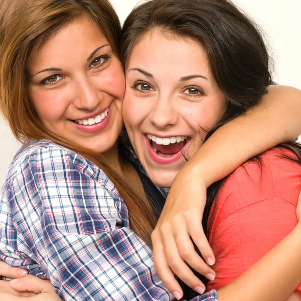 Caucasian sisters embracing, laughing at camera
