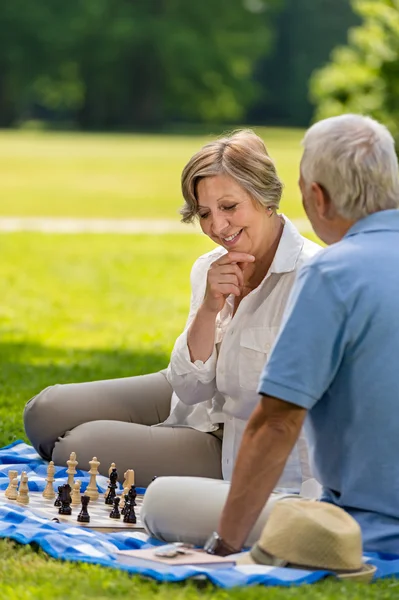 Elderly friends couple playing chess outdoors