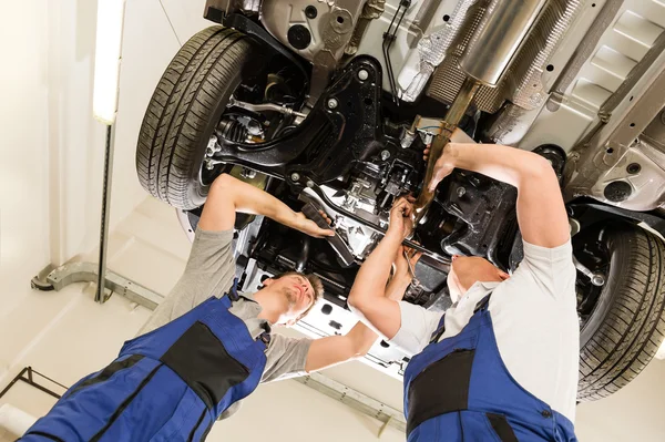 Auto mechanics working underneath a car