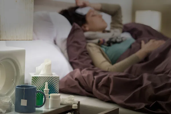 Tissue, flu medicines ill woman bedside table