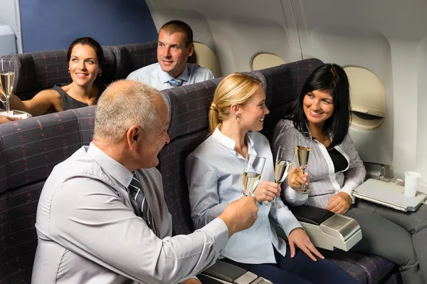 Airplane cabin businesspeople toasting champagne