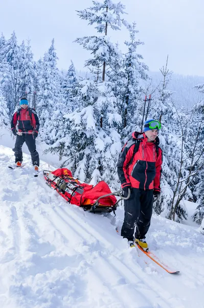 Ski patrol transporting injured skier snow forest