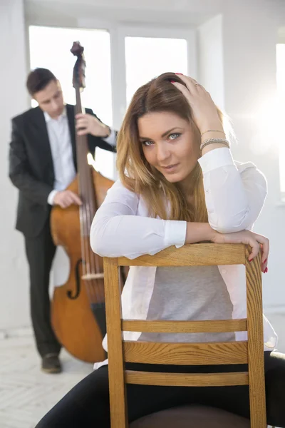 Woman on chair and man with contrabass
