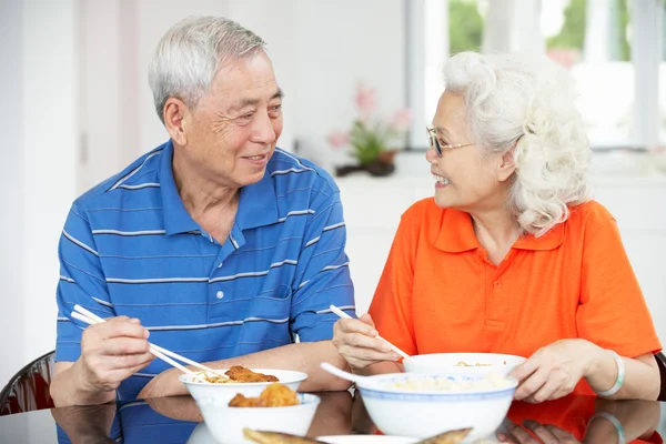 Senior Chinese Couple Sitting At Home Eating Meal