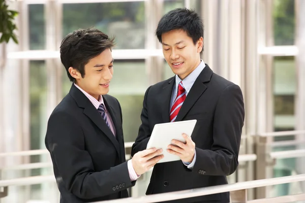 Two Chinese Businessmen Using Tablet Computer Outside Office