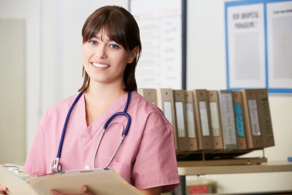 Nurse Reading Patient Notes At Nurses Station