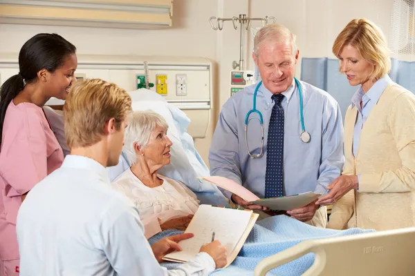 Medical Team Visiting Senior Female Patient In Bed