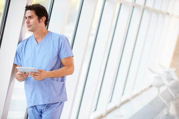 Doctor Using Digital Tablet In Corridor Of Modern Hospital