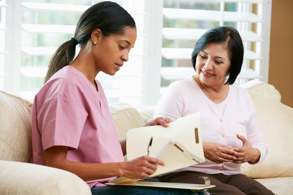 Nurse Discussing Records With Senior Female Patient During Home