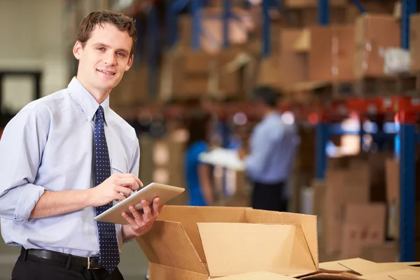 Manager In Warehouse Checking Boxes Using Digital Tablet