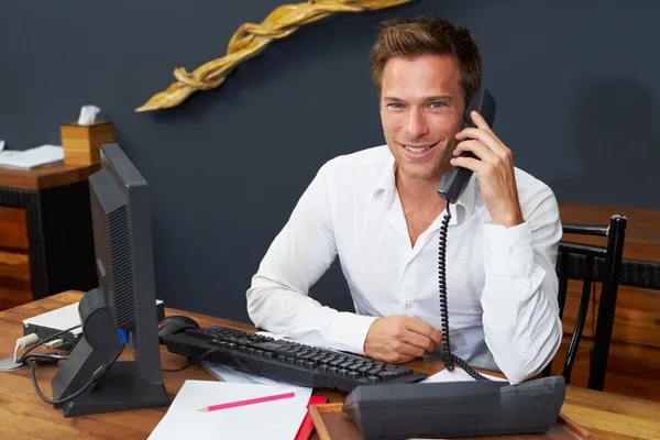 Hotel Receptionist Using Computer And Phone