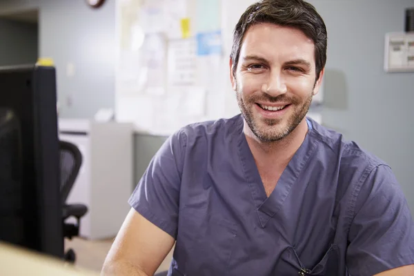 Portrait Of Male Nurse Working At Nurses Station