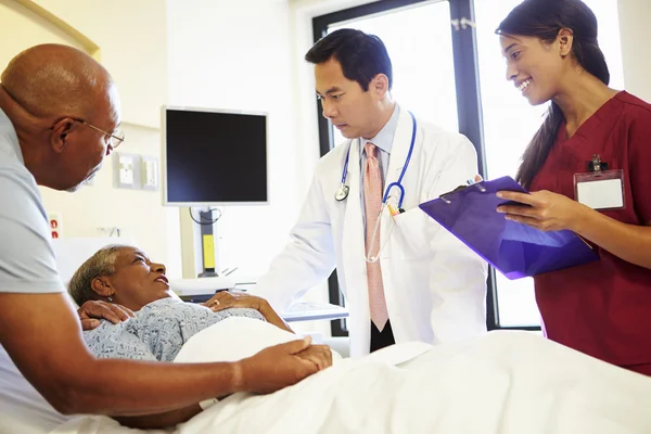 Medical Team Meeting With Senior Couple In Hospital Room