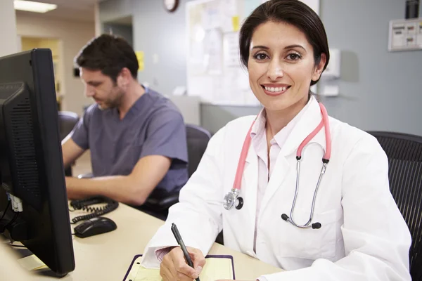 Female Doctor With Male Nurse Working At Nurses Station