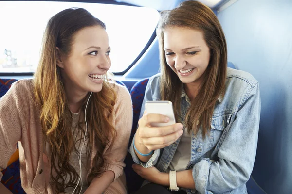 Two Young Women Reading Text Message On Bus