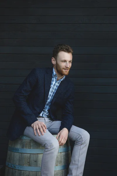 Man in a jacket sitting on a barrel