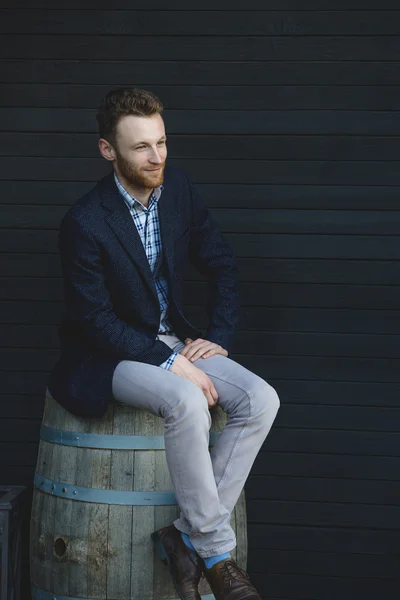 Man in a jacket sitting on a barrel