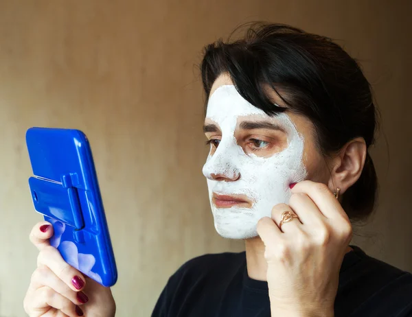 Beautiful woman gets cosmetic mask in the mirror