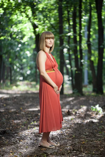Young happy pregnant woman relaxing and enjoying life in nature