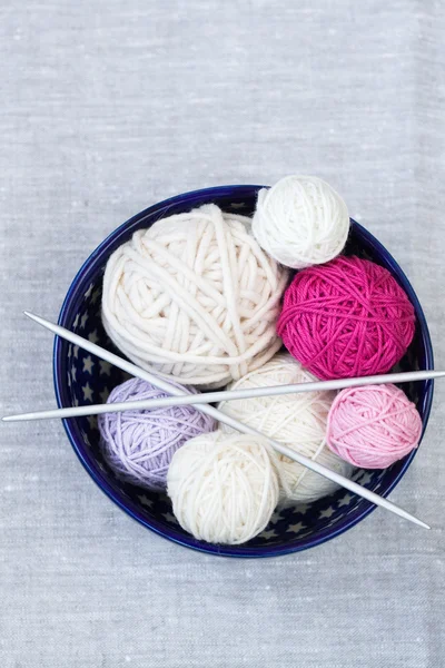 Bright balls of yarn and knitting needles on a plate