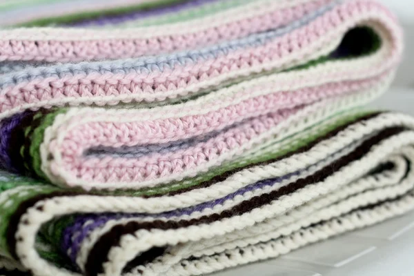 Knitting striped rug with white, purple, green and pink stripes