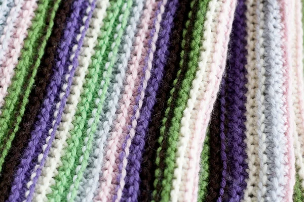 Knitting striped rug with white, purple, green and pink stripes
