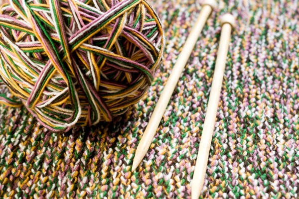 Great ball of colored yarn, wooden knitting needles and knit fabric