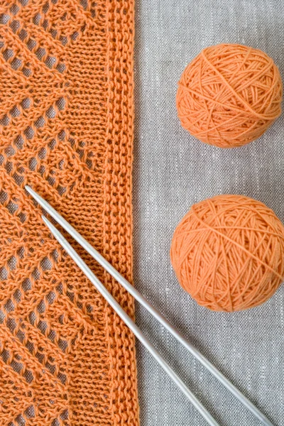 Orange balls, knitted pattern and knitting needles