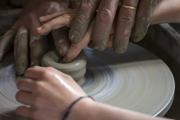Potter shaping a ceramic plate on a pottery wheel