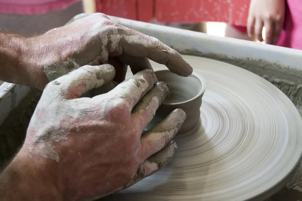 Potter shaping a ceramic plate on a pottery wheel