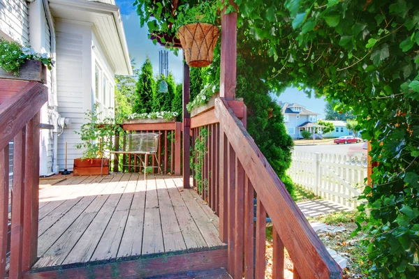 Small old deck with fence and white house.