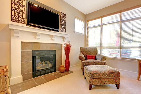 Fireplace with large TV above, elegant chair with windows.