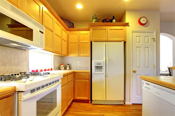 Kitchen with yellow wood cabinets and white appliances.