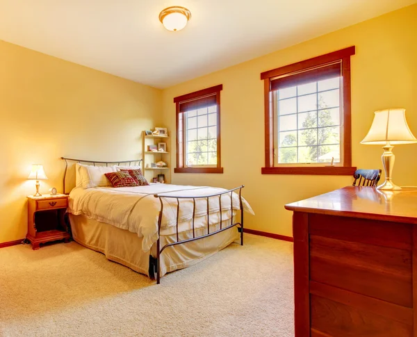 Large bedroom with metal bed and two windows.