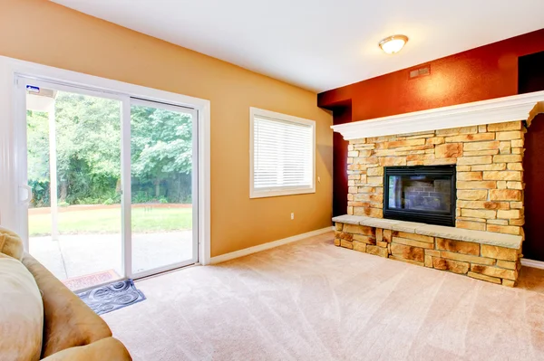 Empty Living room with large fireplace and door to backyard.