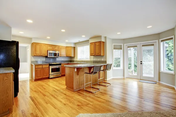 Large empty open kitchen with living room with balcony doors.