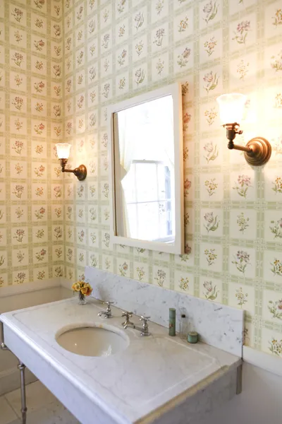 Historical antique bathroom with wallpaper and marble sink.