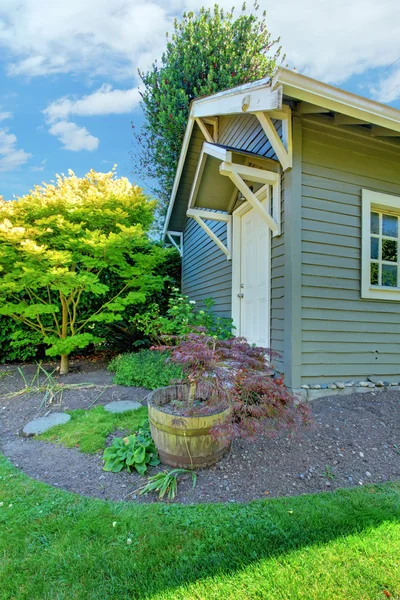 Grey small outdoor shed with backyard landscape.