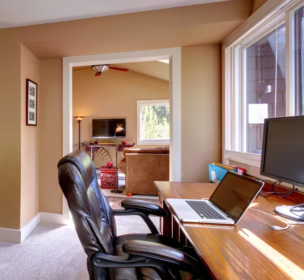 Home office and computer and chair with brown walls.