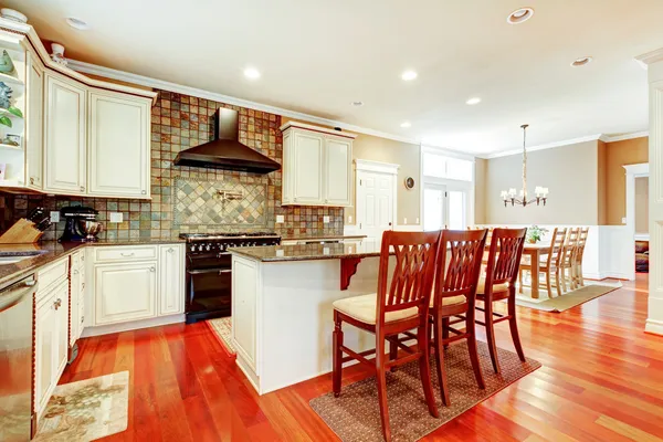 Luxury white kitchen with cherry hardwood and island with chairs.