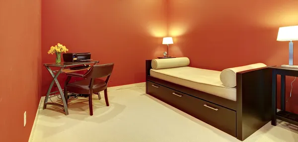Red room with sofa bed and office desk.