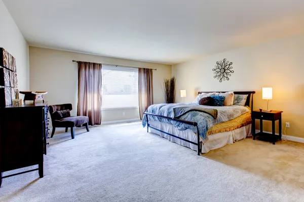 Large bedroom with beige carpet and black bed.