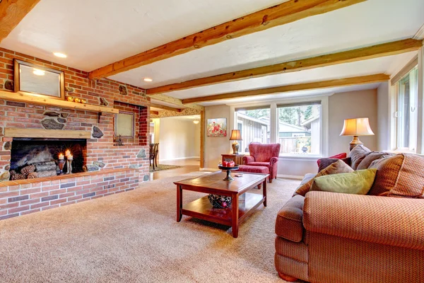 Living room interior with brick fireplace, wood beams and red.