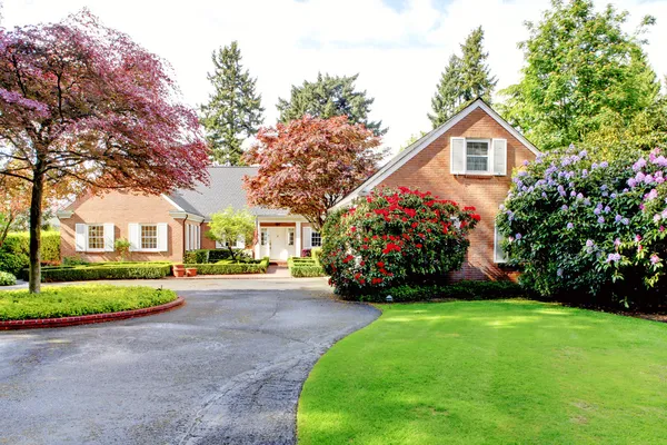 Brick red house with English garden and white window shutters.