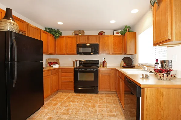 Brown kitchen cabinets with black appliances