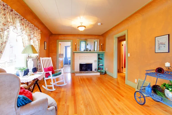 Orange spacious living room with antique cart, rocking chair