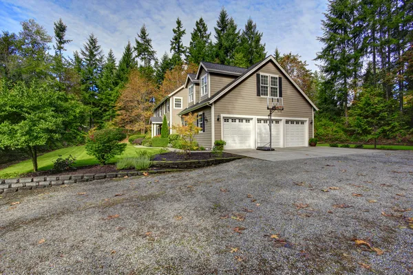 House exterior. View of three car garage with driveway and baske